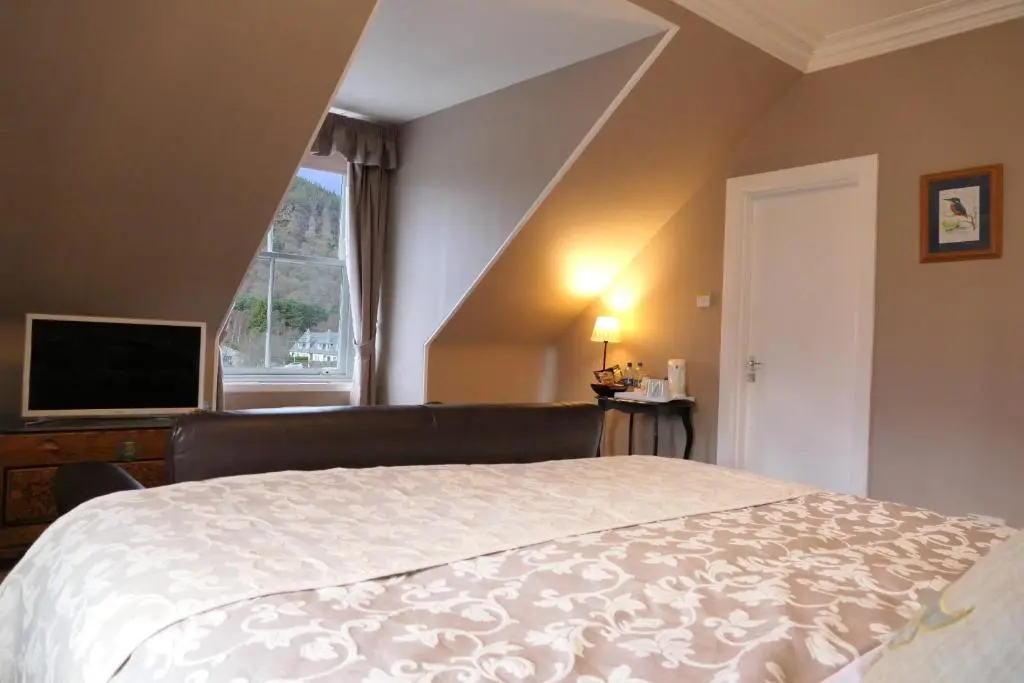 a bedroom with a large bed and a window at The Gordon Guest House in Ballater