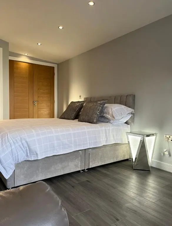 a bedroom with a large bed and a wooden floor at Wee Coastal Snug in Wick