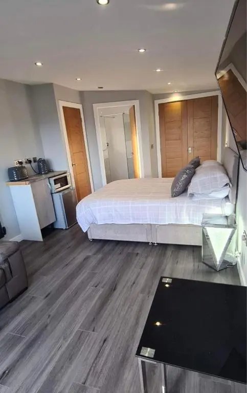 a bedroom with a large bed and a living room at Wee Coastal Snug in Wick