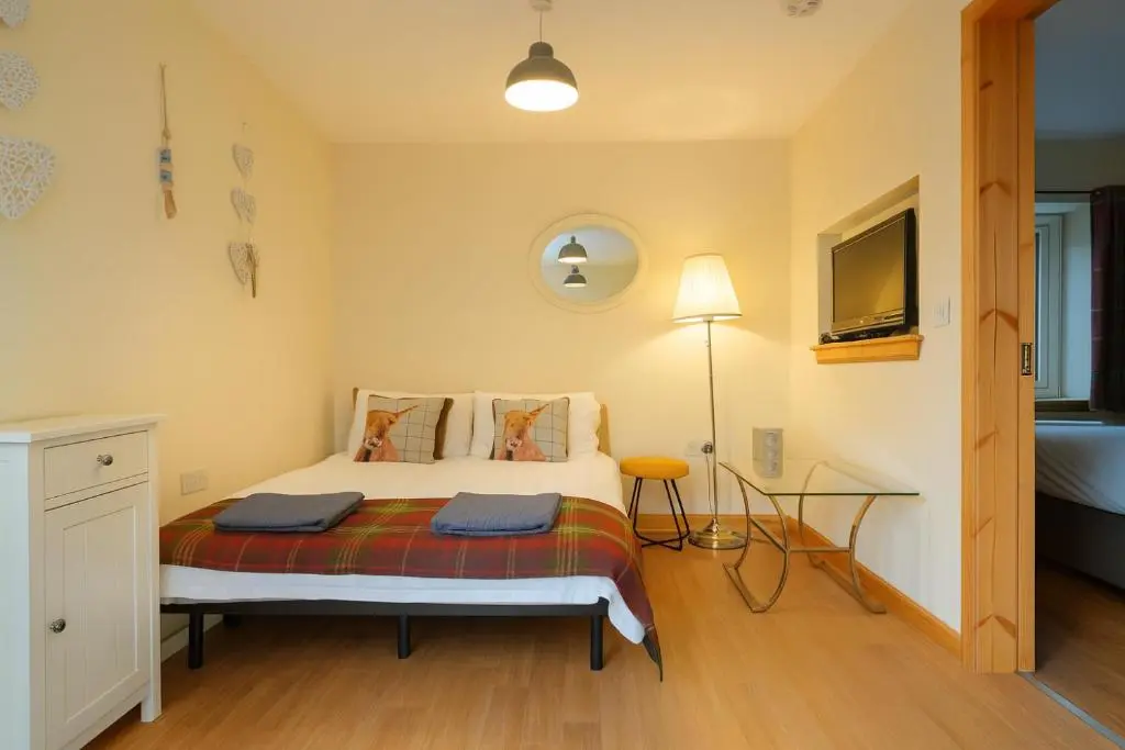 a bedroom with a bed and a desk and a television at Tanera in Inverness