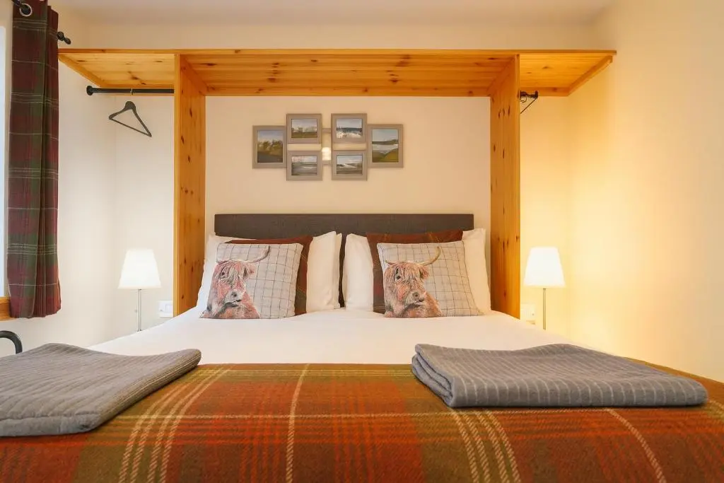 a bedroom with a large bed with a wooden canopy at Tanera in Inverness