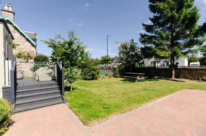 a garden with a wooden staircase and a picnic table at Sweeney Aviemore Two in Aviemore