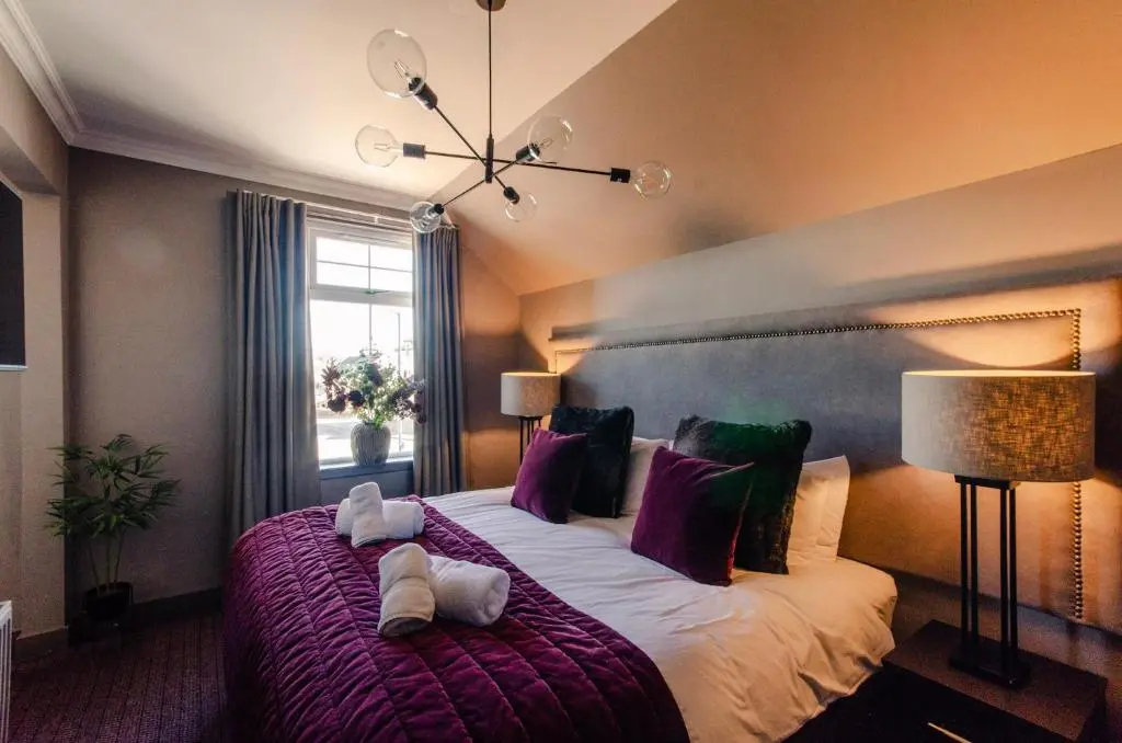 a bedroom with a large bed with pillows and a window at Sweeney Aviemore Two in Aviemore