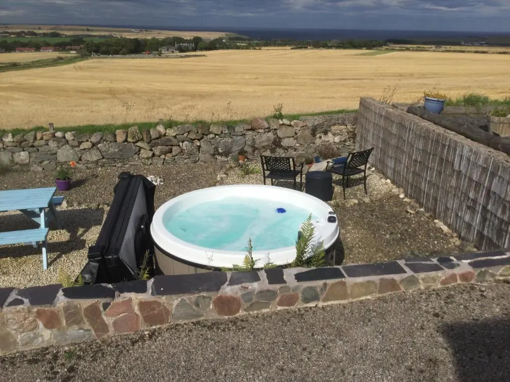 a bath tub sitting in a yard with two chairs at The Brae Steading in Fordyce