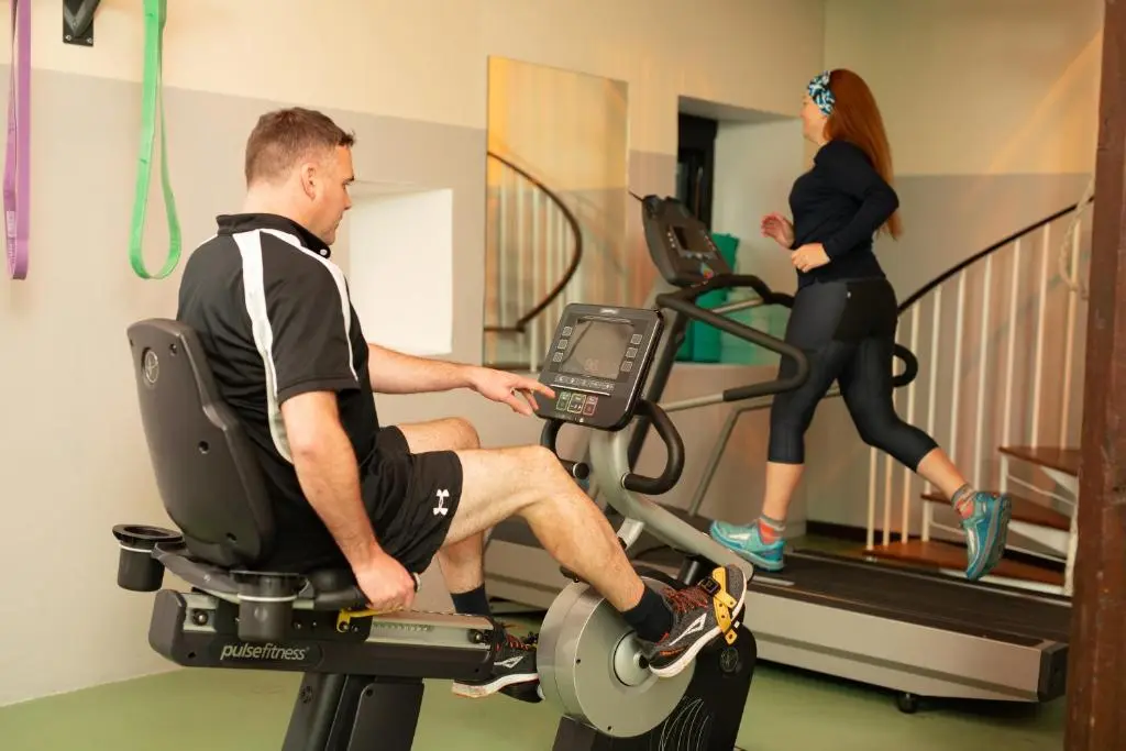 a man riding a exercise bike in a gym with a woman at Swiss Chalet Balnagown Castle in Kildary