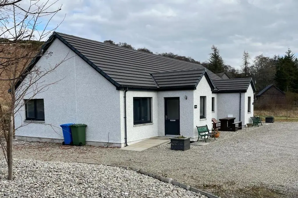 a small white house with a black roof at Highland Holiday Lets Lairg in Lairg