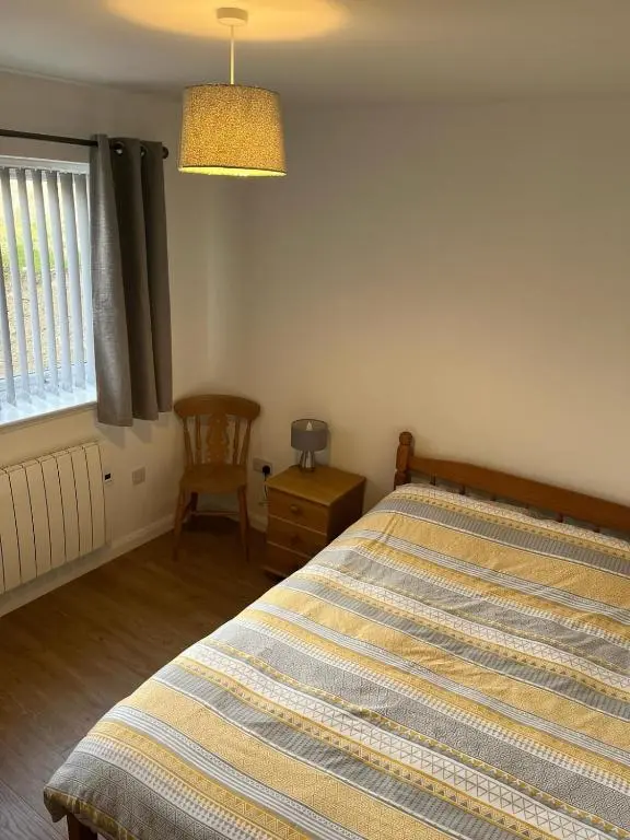 a bedroom with a bed and a chair and a window at Highland Holiday Lets Lairg in Lairg