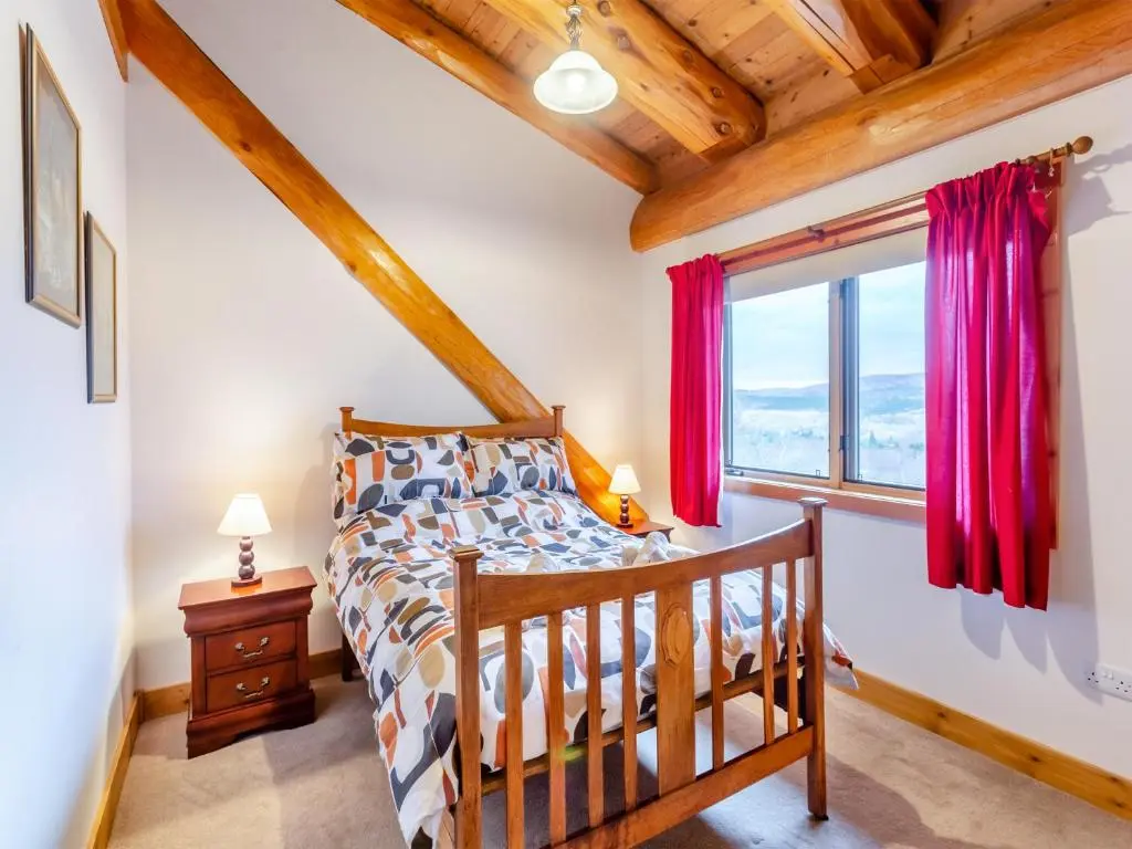 a bedroom with a bed and a window at Molalatau Lodge in Lairg