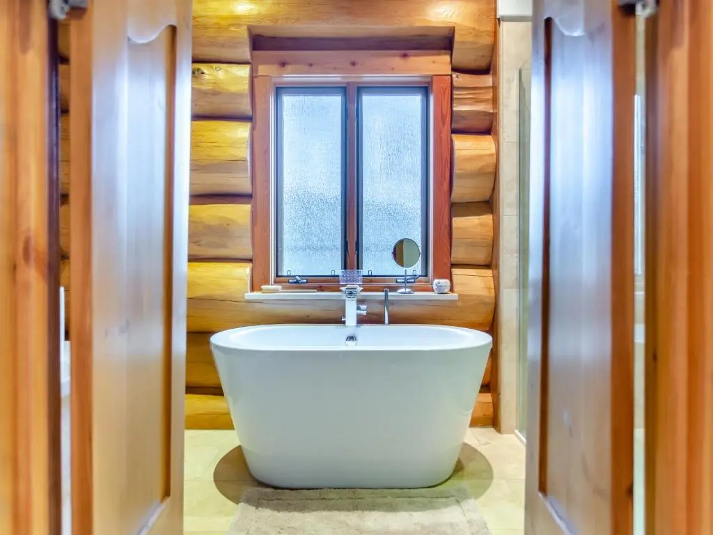 a bathroom with a bath tub in front of a window at Molalatau Lodge in Lairg