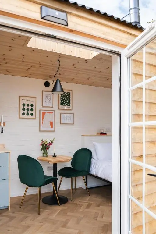 a room with a bed and a table and chairs at Willow's Nordic Shepherds Hut in Ballater