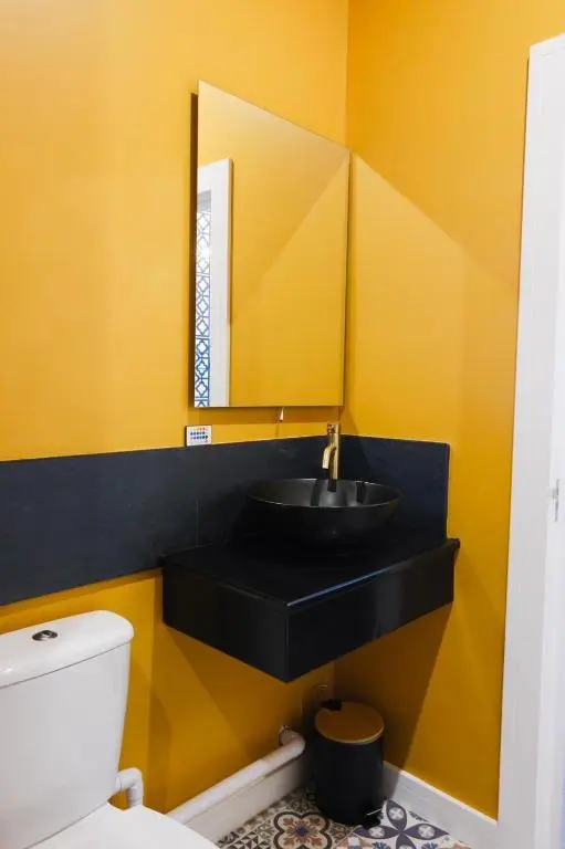 a bathroom with a black sink and a yellow wall at Inbhir Nis City Apartment in Inverness