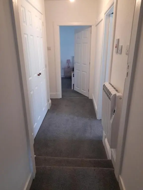 a hallway with white doors and a room with a heater at Culbokie Inn on the NC500 in Culbokie