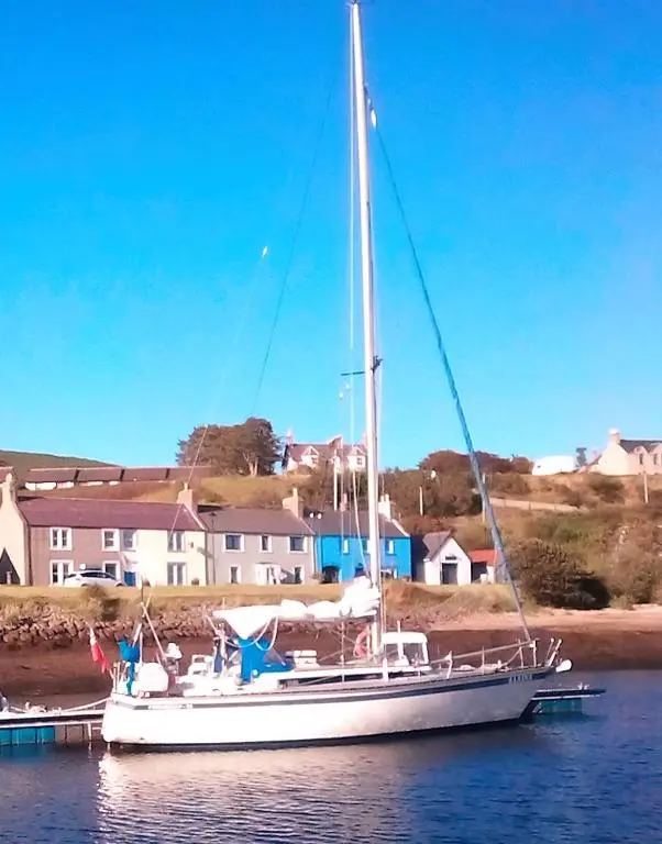 a sailboat docked in the water with houses in the background at Selkie House Song of the Sea in Helmsdale