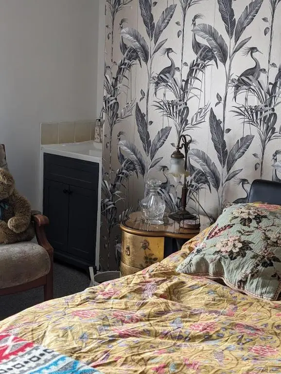 a bedroom with a bed with a floral wallpaper at Selkie House Sea Song in Helmsdale
