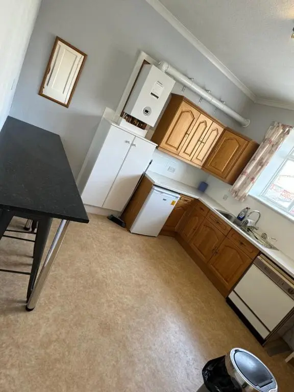 an empty kitchen with white appliances and wooden cabinets at Spacious Harbour House in Wick