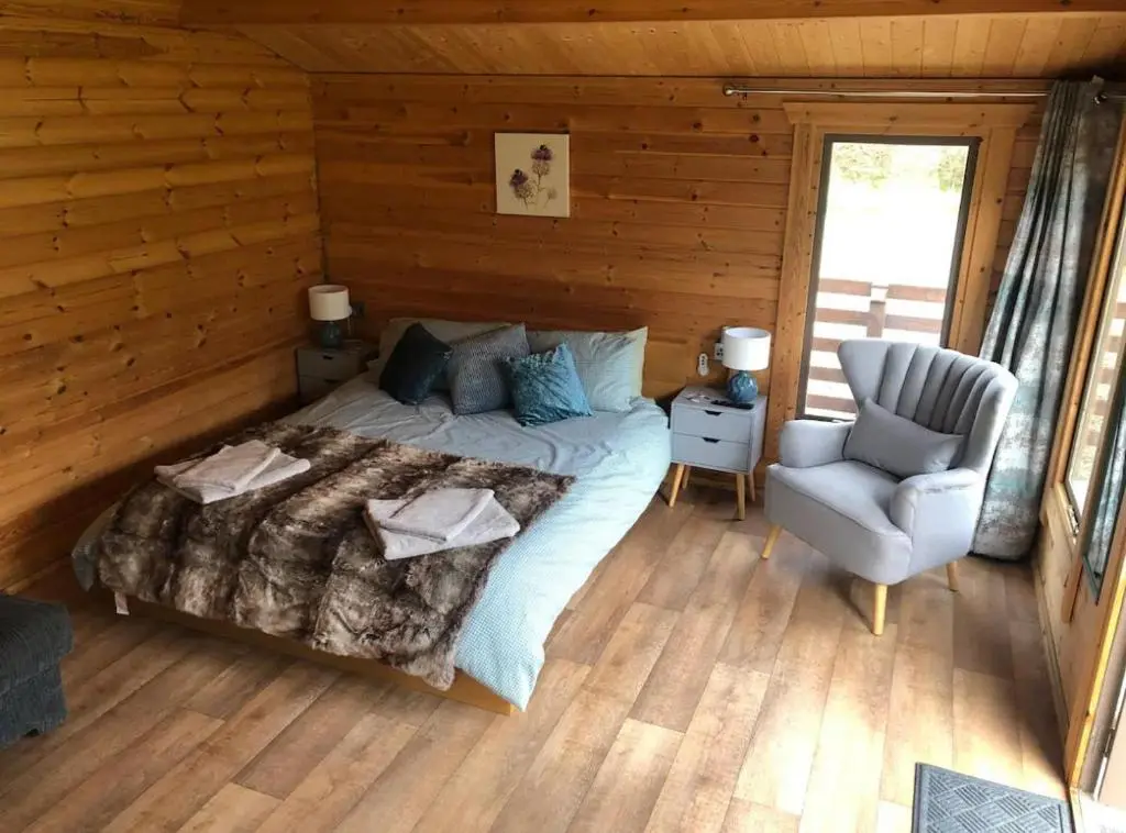 a bedroom with a bed and a chair in a cabin at Backieley Lodge in Huntly