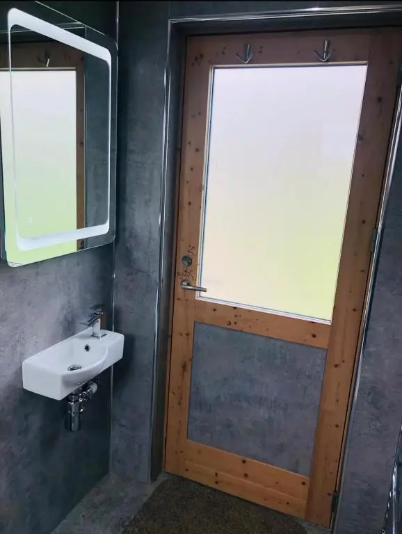 a bathroom with a wooden door and a sink at Backieley Lodge in Huntly