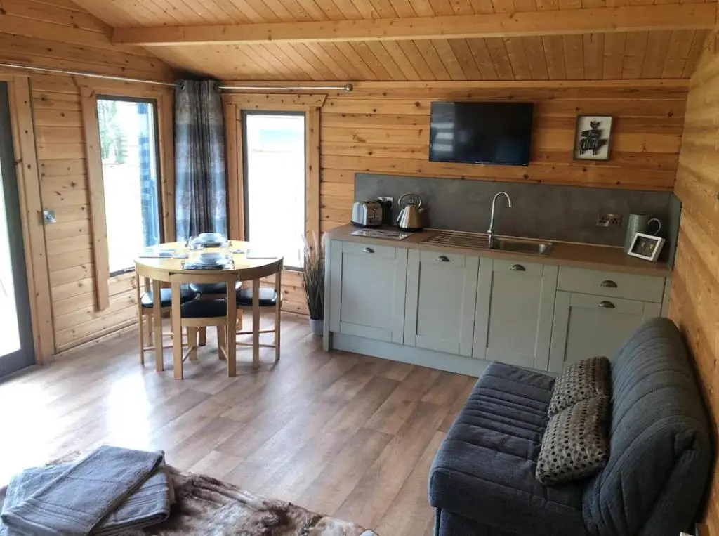 a kitchen and a living room with a couch and a table at Backieley Lodge in Huntly