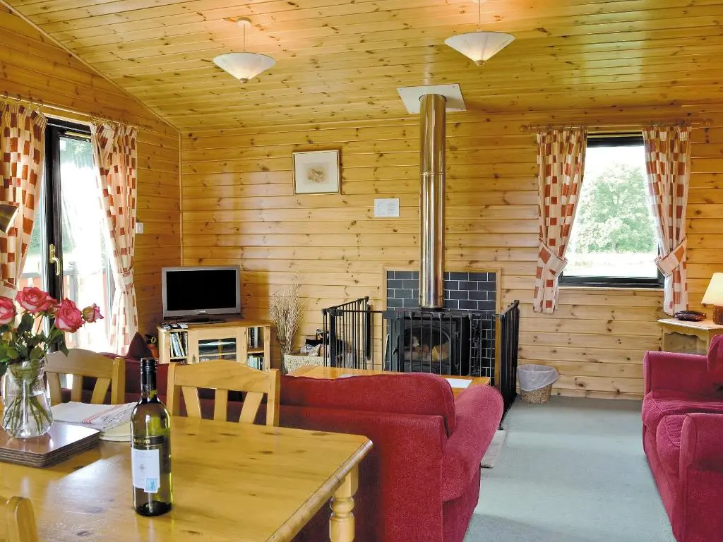 a living room with red furniture and a fireplace at Larch Cottage - S4428 in Kirkton of Glenisla