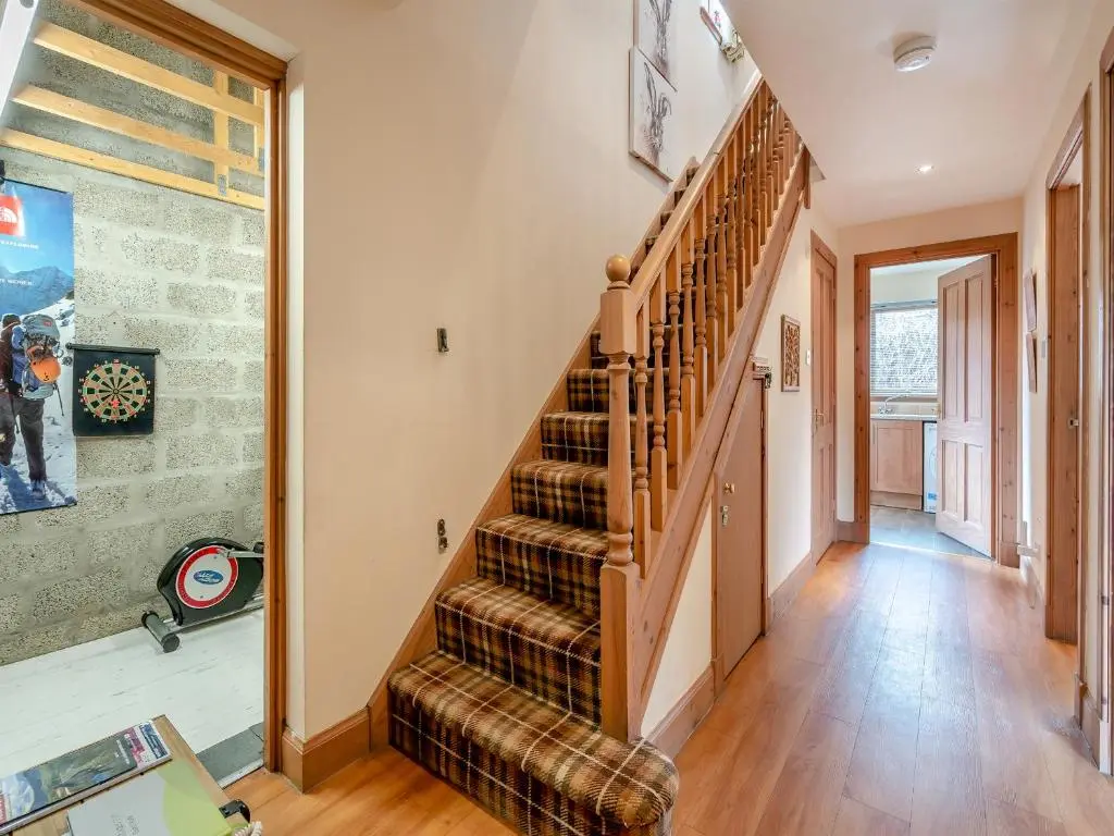 a staircase in a living room with wooden floors at Coire Cas - S4538 in Inverdruie