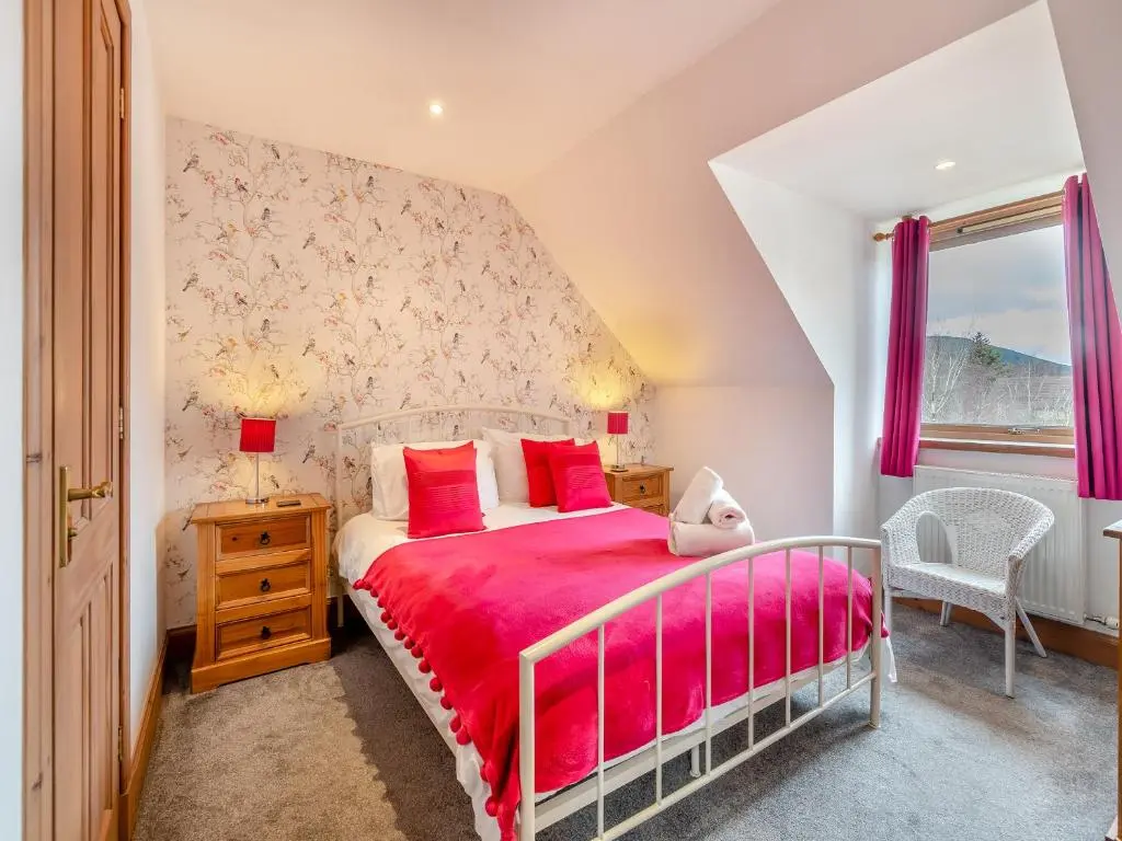 a bedroom with a bed with a red bedspread at Coire Cas - S4538 in Inverdruie