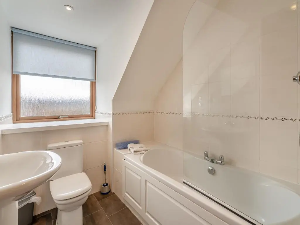 a white bathroom with a tub and a toilet and a sink at Clunnie Mor - S4615 in Aviemore