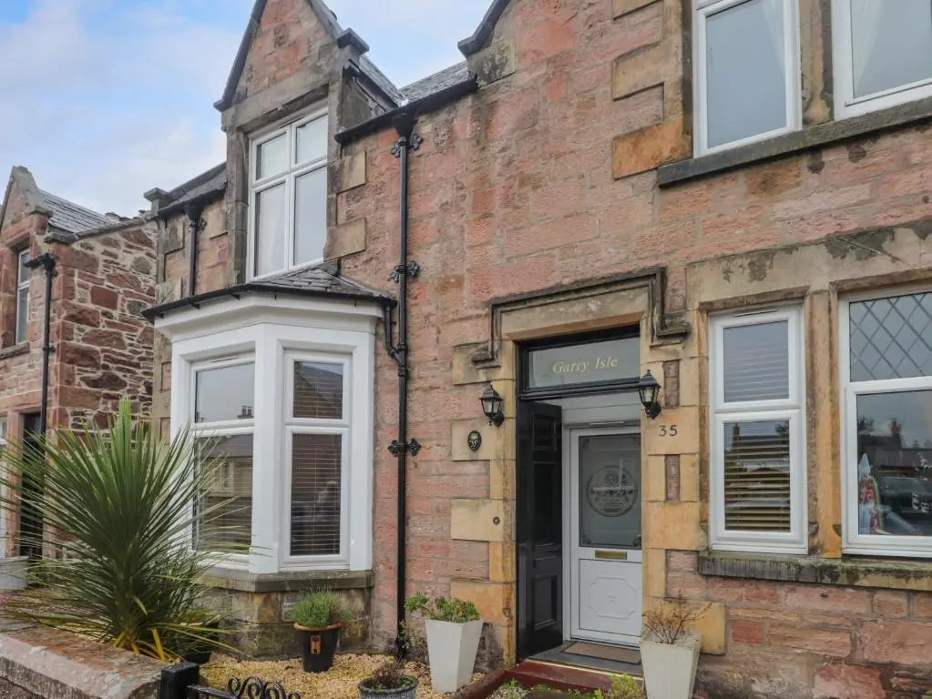an old brick house with a white door at Garry Isle in Inverness