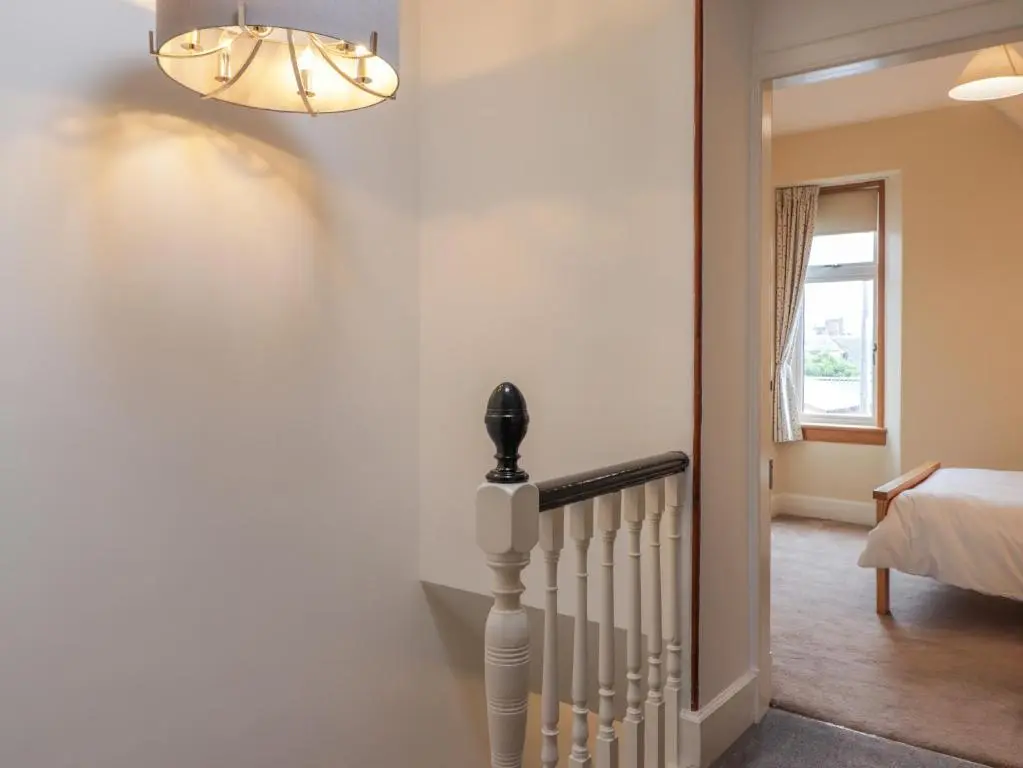 a hallway with a staircase and a chandelier at Garry Isle in Inverness