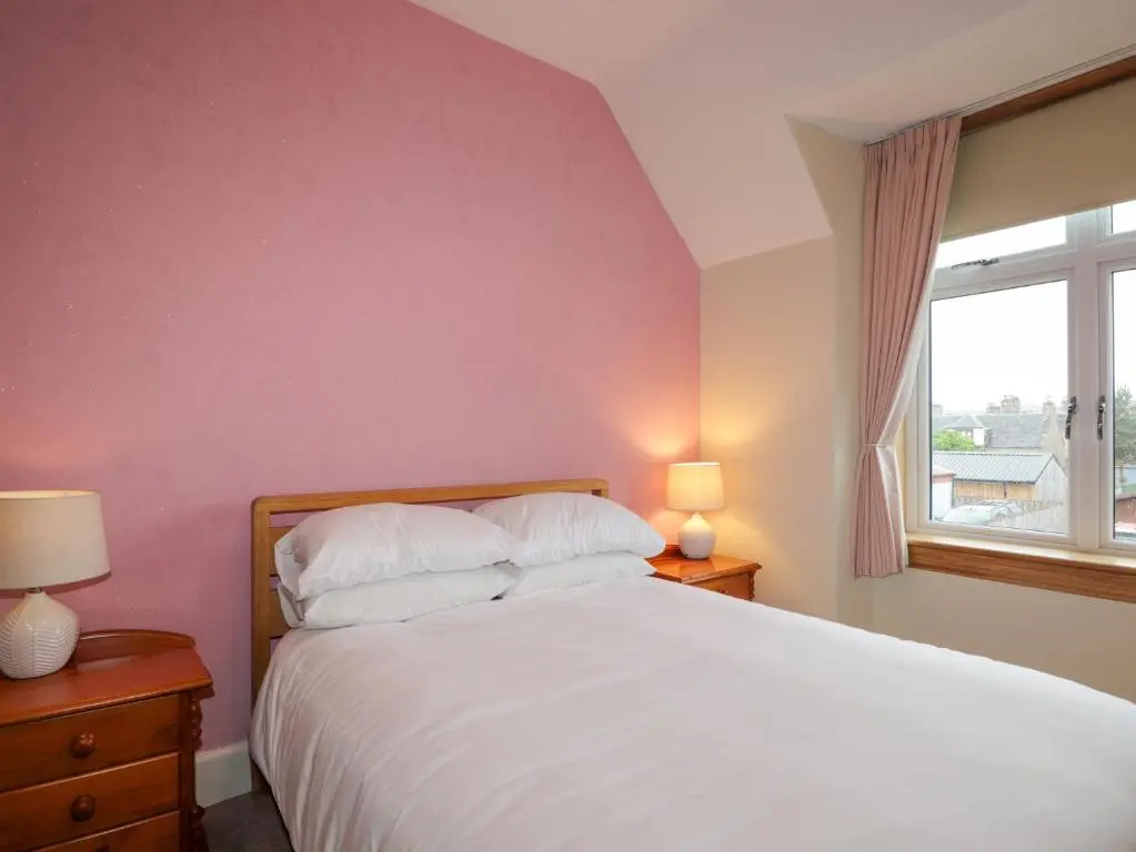 a bedroom with a white bed and a window at Garry Isle in Inverness