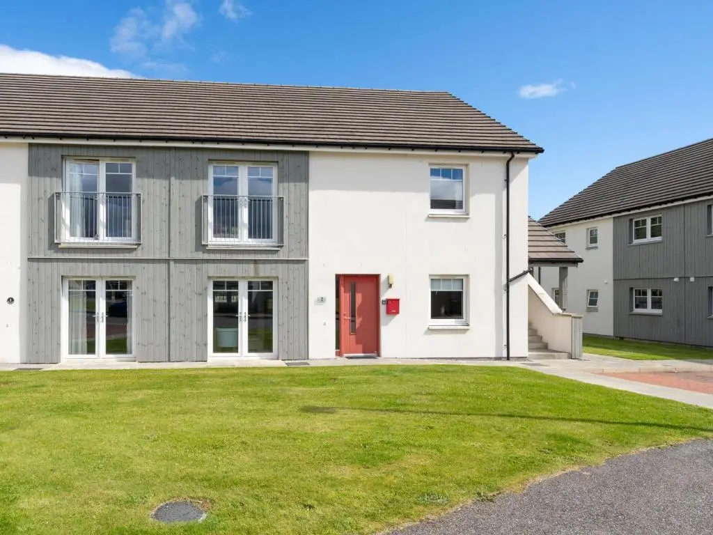 a house with a red door and a yard at Apartment The Muir by Interhome in Aviemore