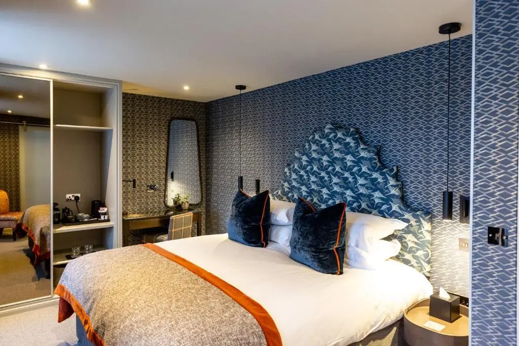 a bedroom with a large bed with a blue wall at Hotel 1881 of Speyside in Archiestown