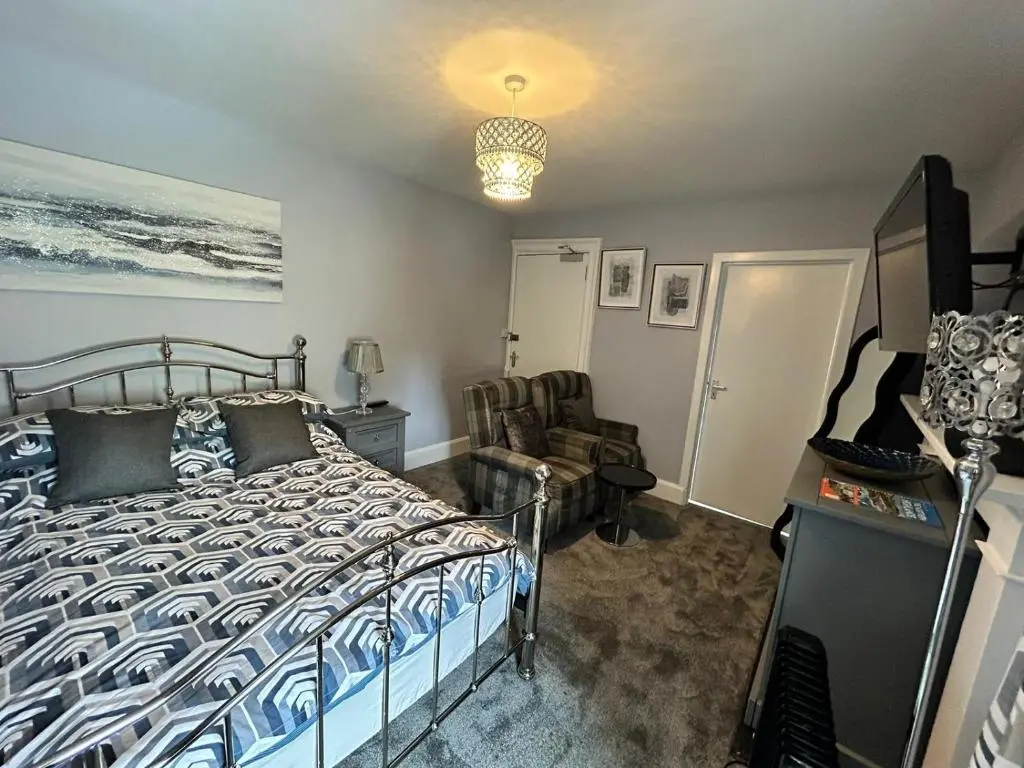 a bedroom with a bed and a chair at St Duthus Hotel in Tain