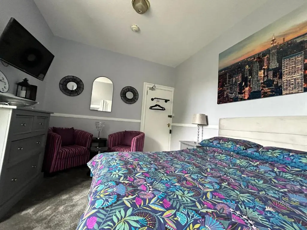 a bedroom with a bed and two red chairs at St Duthus Hotel in Tain