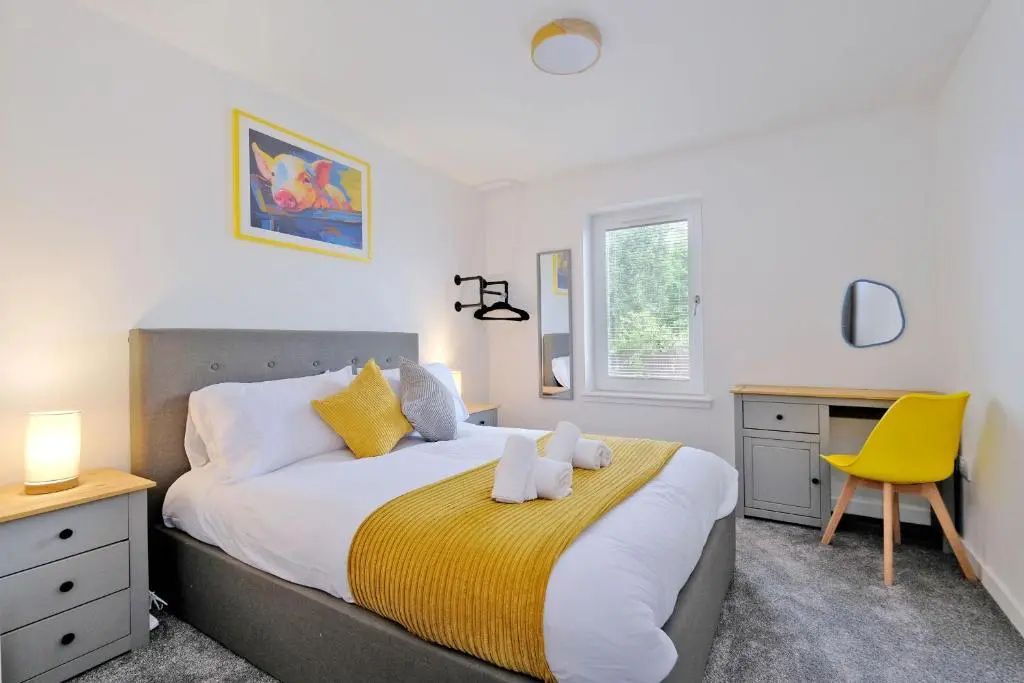 a bedroom with a large bed and a yellow chair at Contemporary Luxury Lodge, Aberdeen West in Blackburn