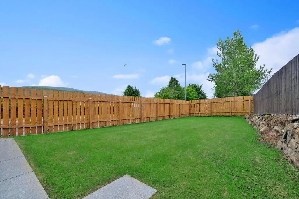 a wooden fence in a yard with a green lawn at Contemporary Luxury Lodge, Aberdeen West in Blackburn