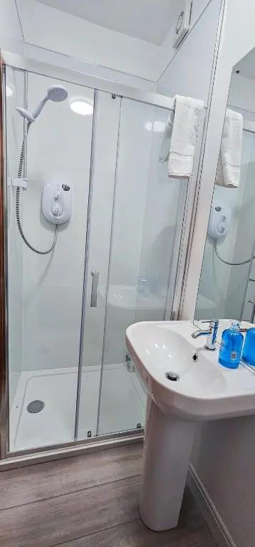 a white bathroom with a shower and a sink at Melrose Villa 11 Bedroom House in Inverness