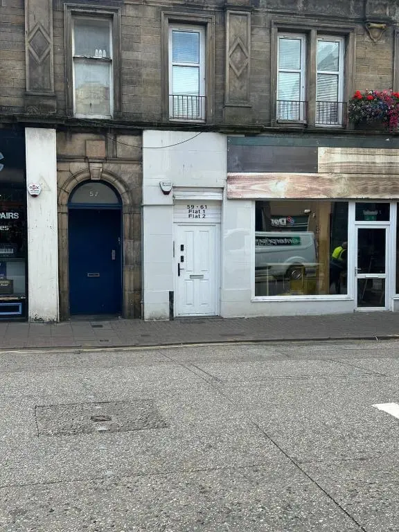 a white building with a blue door on a street at MacIver City Apartment Academy Street in Inverness