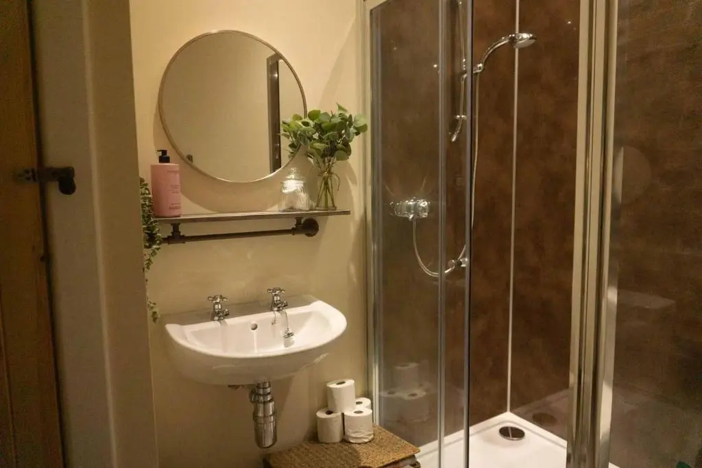 a bathroom with a sink and a shower with a mirror at The Potted Pineapple in Oyne