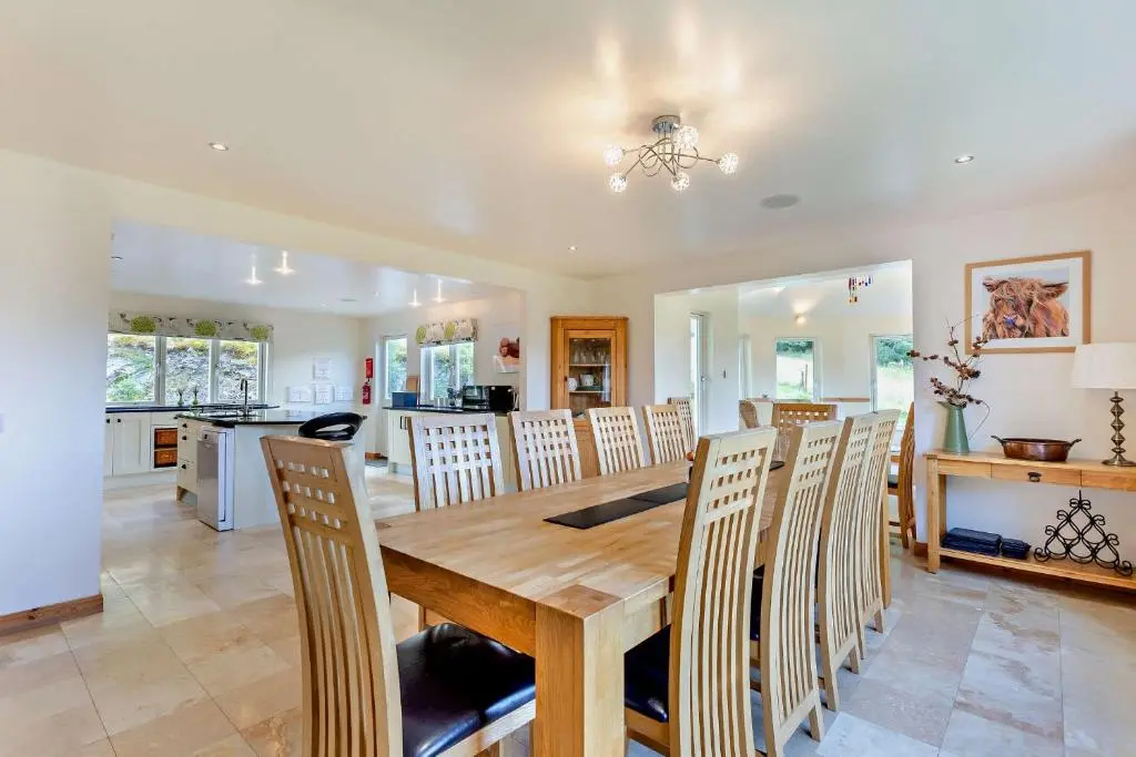 a kitchen and dining room with a wooden table and chairs at Sealladh an Loch in Foyers