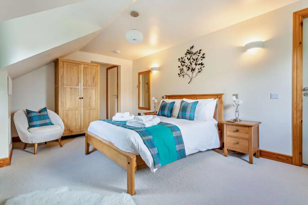 a bedroom with a large bed and a chair at Sealladh an Loch in Foyers