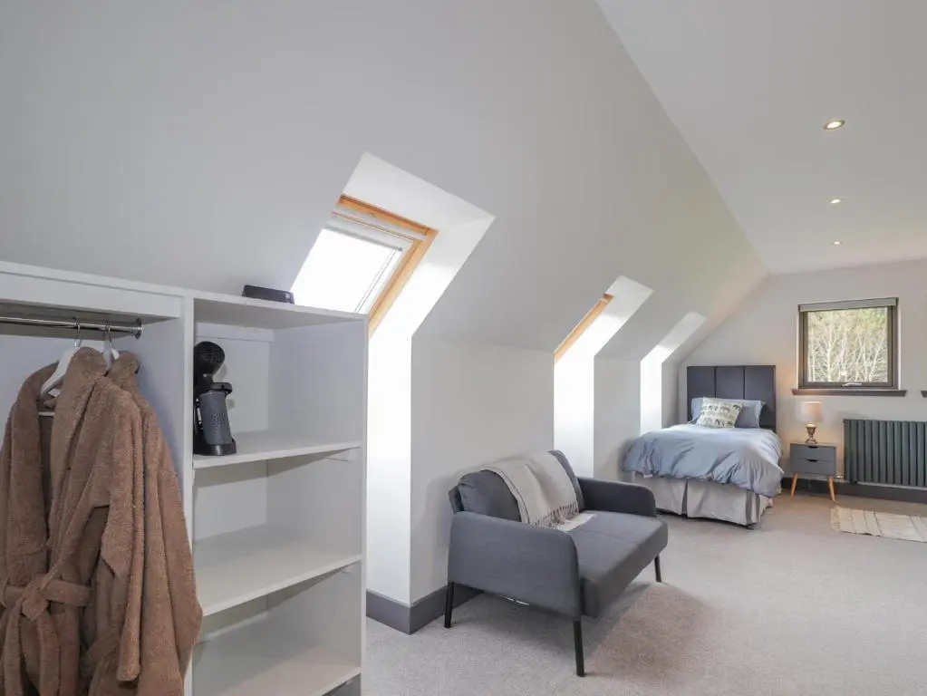 a attic bedroom with a bed and a chair at Ben Luna Lodge in Inverness