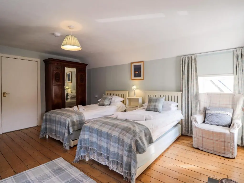 a bedroom with two beds and a chair at Seashell Cottage in Cromarty