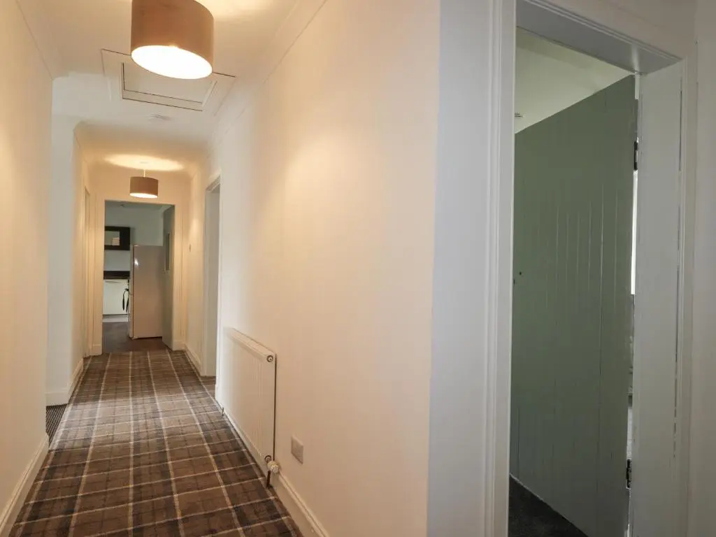 a hallway with a tile floor and a mirror at Apartment in Foyers in Inverness