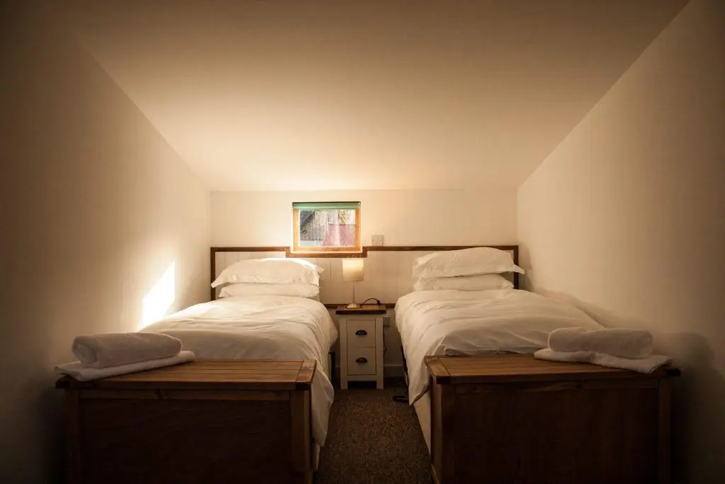 a room with two beds and a night stand in a room at Carn Na Drochaide in Braemar