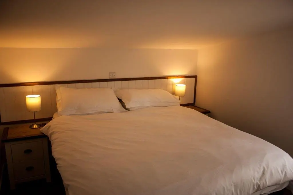 a bedroom with a white bed with two lamps at Choinnich in Braemar