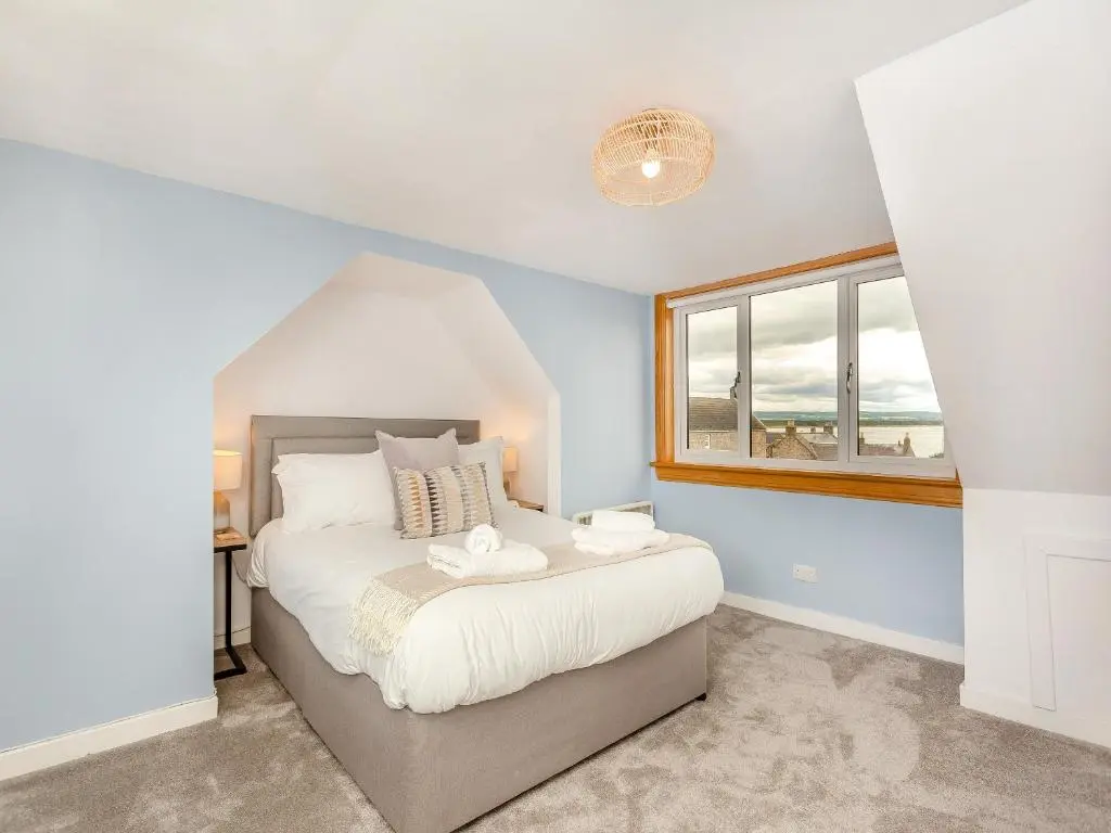a bedroom with a bed and a window at Emerald Cottage in Burghead