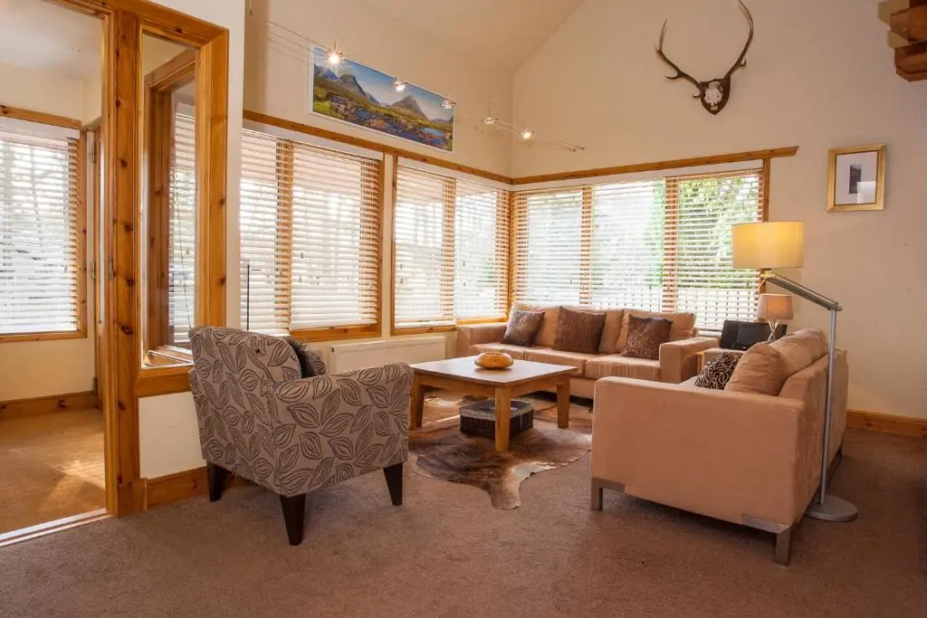 a living room with a couch and chairs and a table at Riverside Lodge Garden Apartment in Aviemore