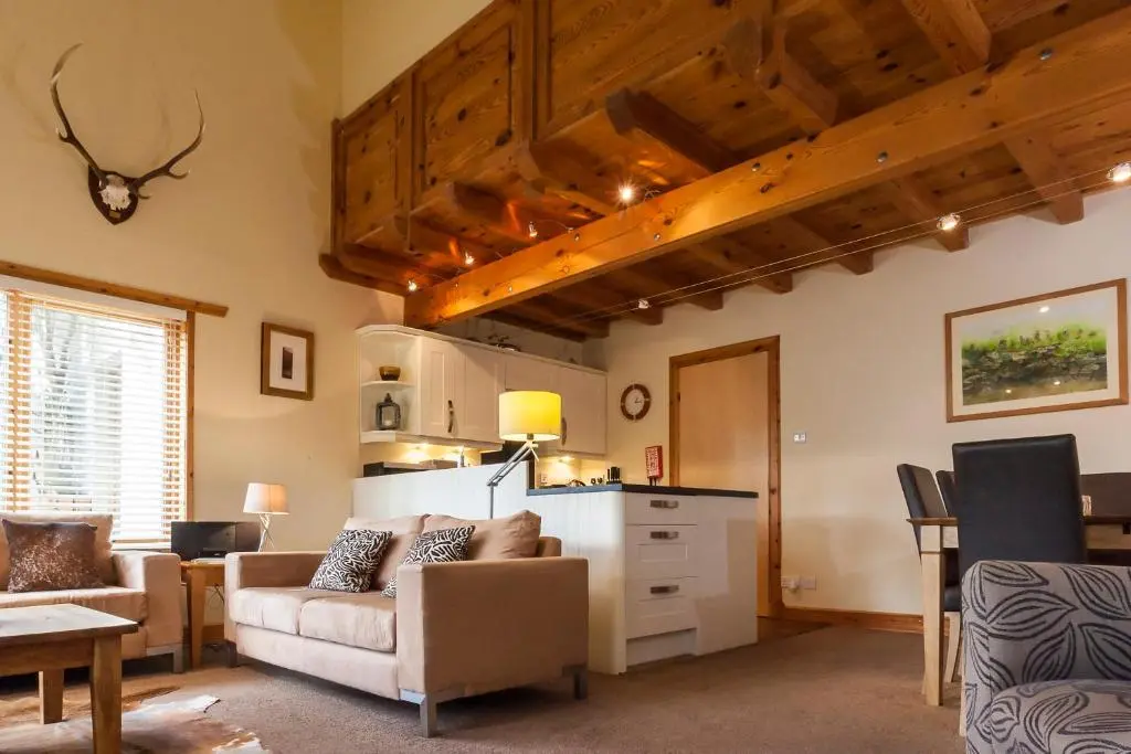 a living room with a couch and a table at Riverside Lodge Garden Apartment in Aviemore