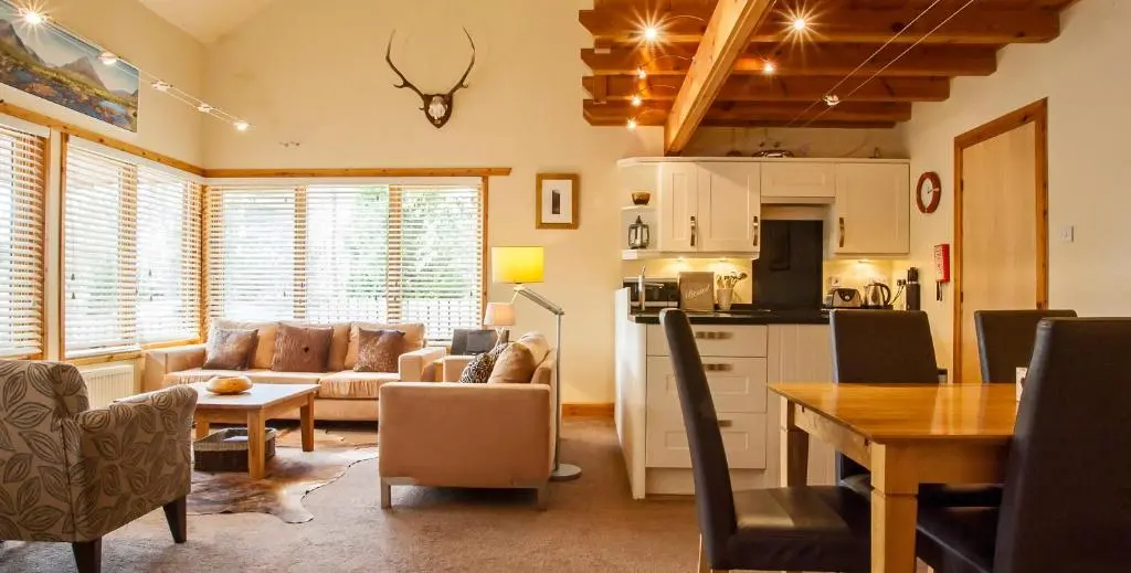 a kitchen and living room with a couch and a table at Riverside Lodge Garden Apartment in Aviemore