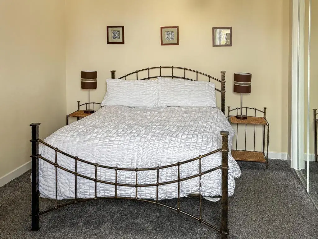 a bed in a bedroom with two lamps on two tables at Ivydene Cottage in Cromarty